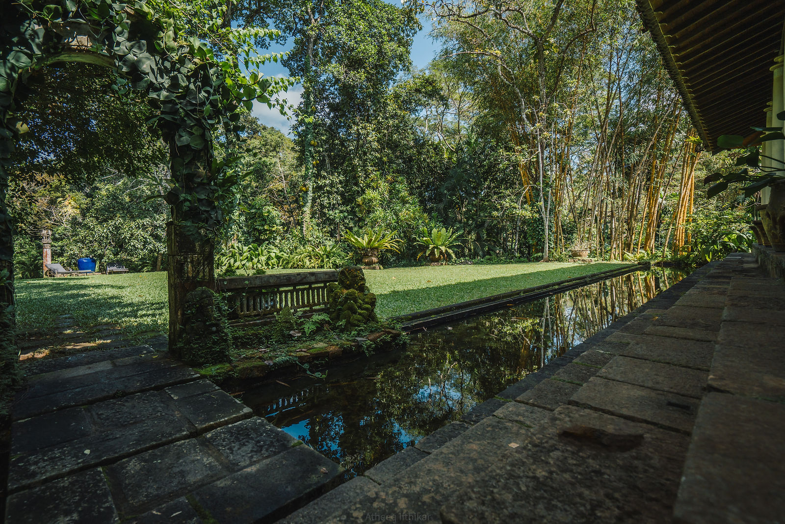 A veranda beside a pond channel in the main house, framed by a vine arch