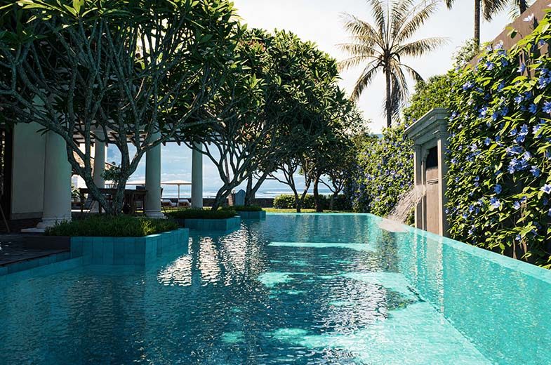 The turquoise pool at IF Villa framed by flowering vines, looking toward the ocean
