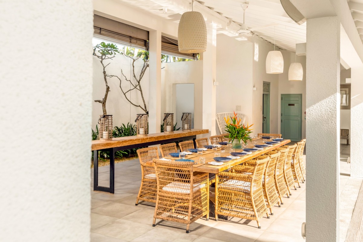 Long wooden dining table with rattan chairs inside the villa's dining hall