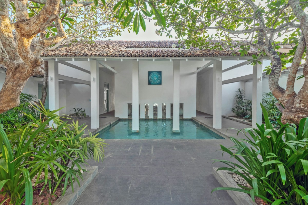 Courtyard swimming pool framed by white columns and frangipani trees