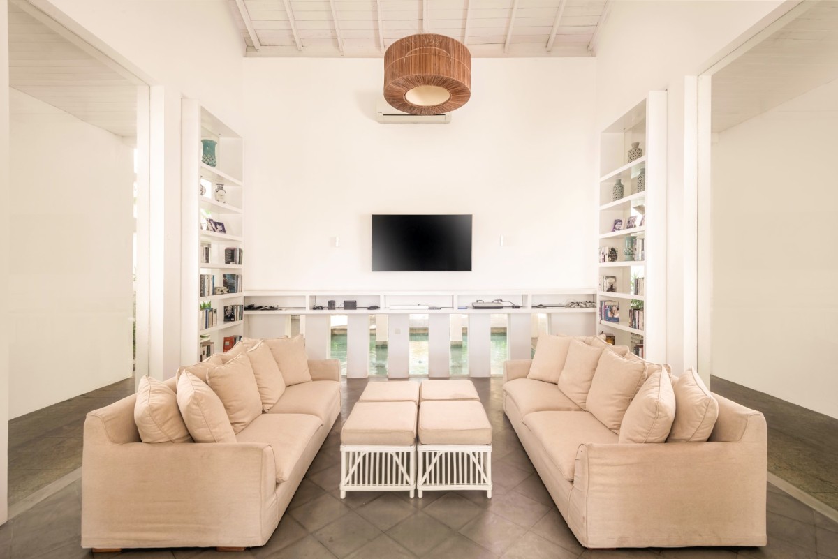 Living room with two long sofas, library shelves and a view through to the pool