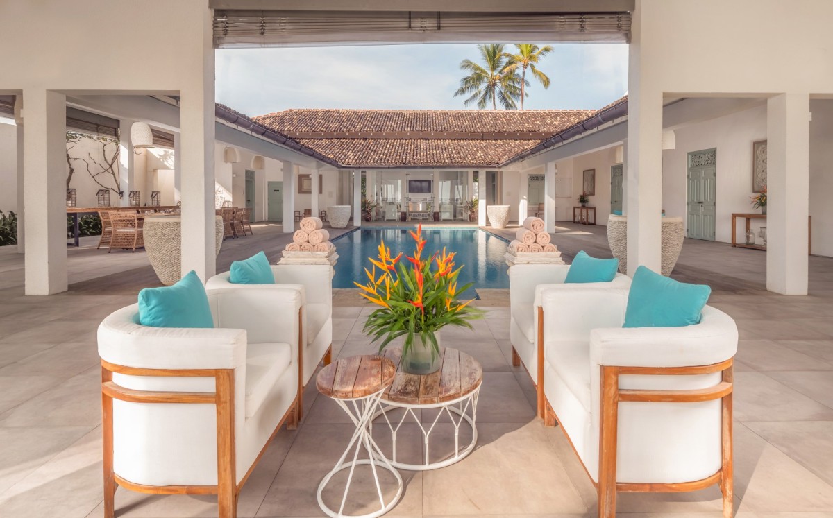 Lounge chairs in the open veranda looking across the courtyard swimming pool