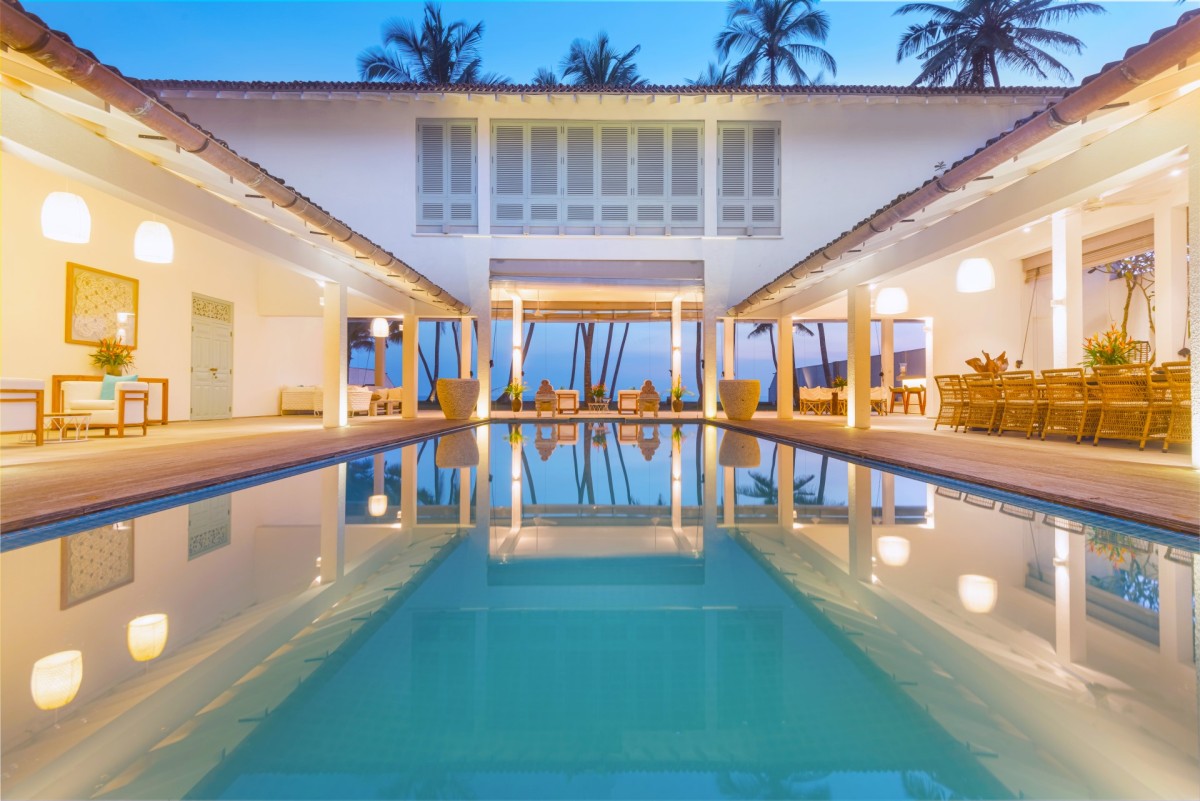 Courtyard pool at dusk reflecting the lit villa, perfectly symmetrical