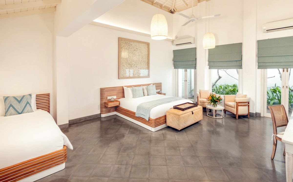 Bedroom 1 at Ishq Talpe — a spacious king bedroom with an additional single bed in the foreground and doors to the garden patio