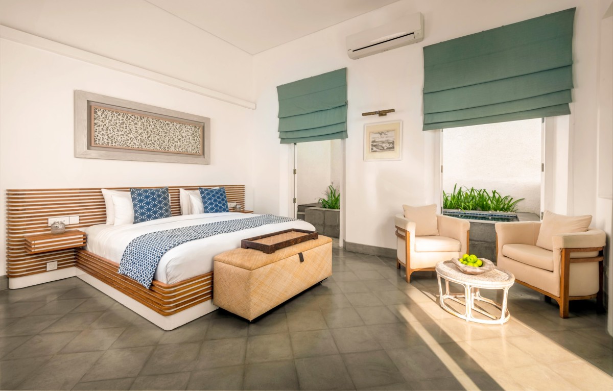 Bedroom 3 at Ishq Talpe — a king bedroom with blue accents and armchairs beside garden-facing doors