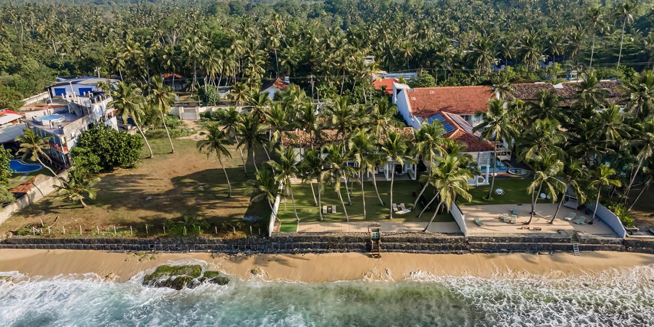 Drone view of Ishq Talpe's beachfront grounds, palms and red-tiled roofs from the ocean side