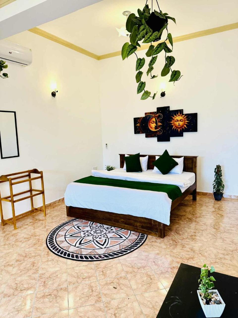 Bedroom with green bedding and sun-and-moon wall art