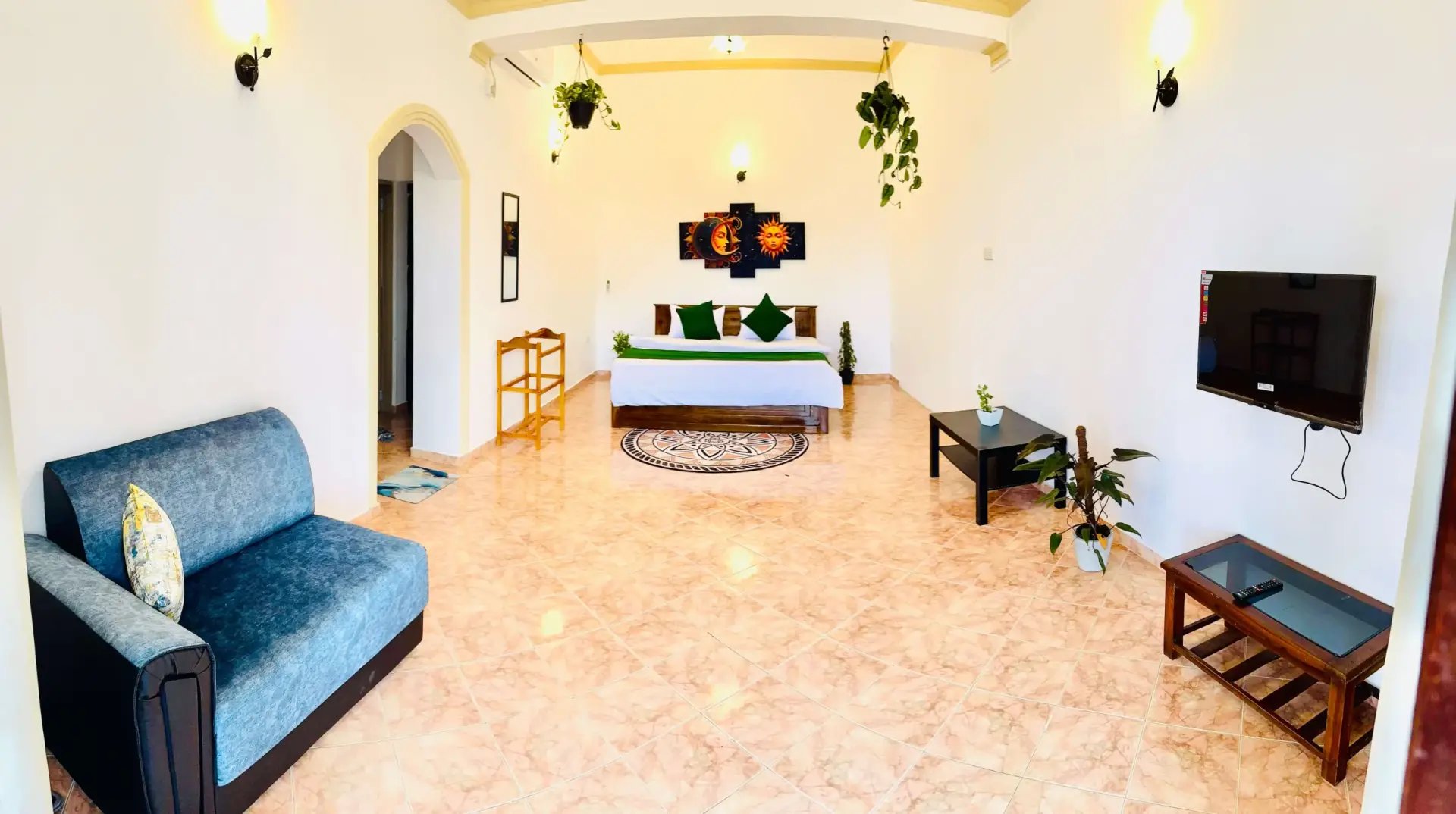 A bedroom suite with green bedding and sun-and-moon wall art