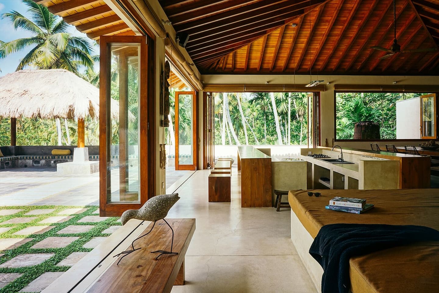 Open-plan living space at Kumara Luxury Villa with floor-to-ceiling bi-fold doors opening onto the pool pavilion