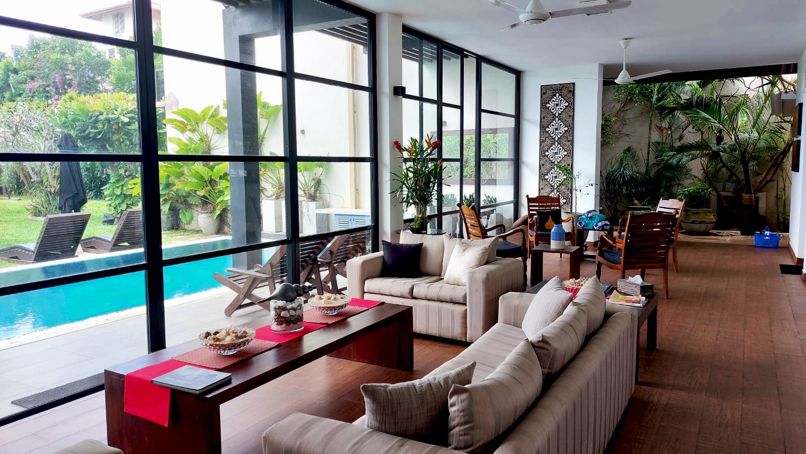 The lounge at Mirissa Beach Villa with glass walls open to the pool terrace