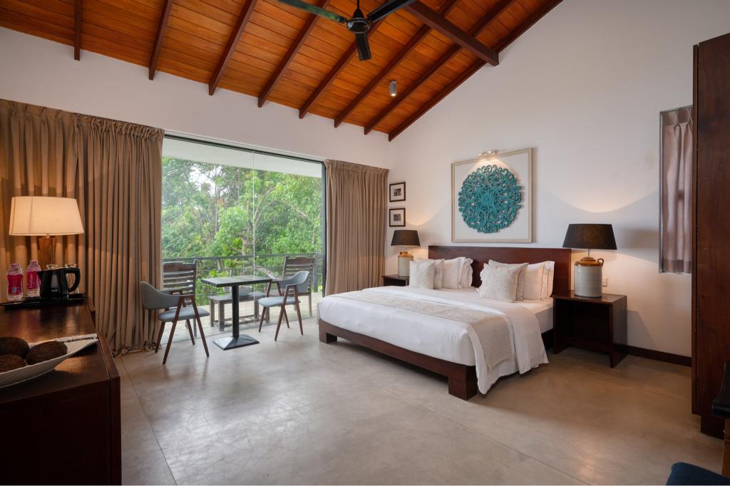 A spacious room at Mirissa Beach Villa beneath a vaulted timber ceiling, opening to the gardens
