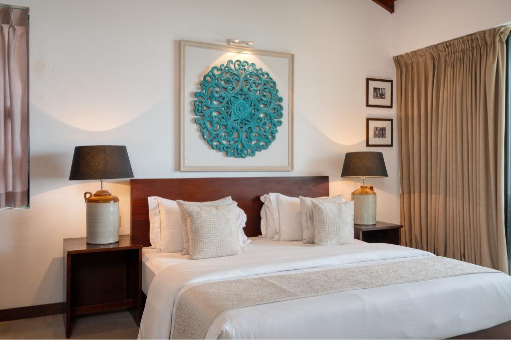 A spacious room at Mirissa Beach Villa with ocean-teal artwork above the bed