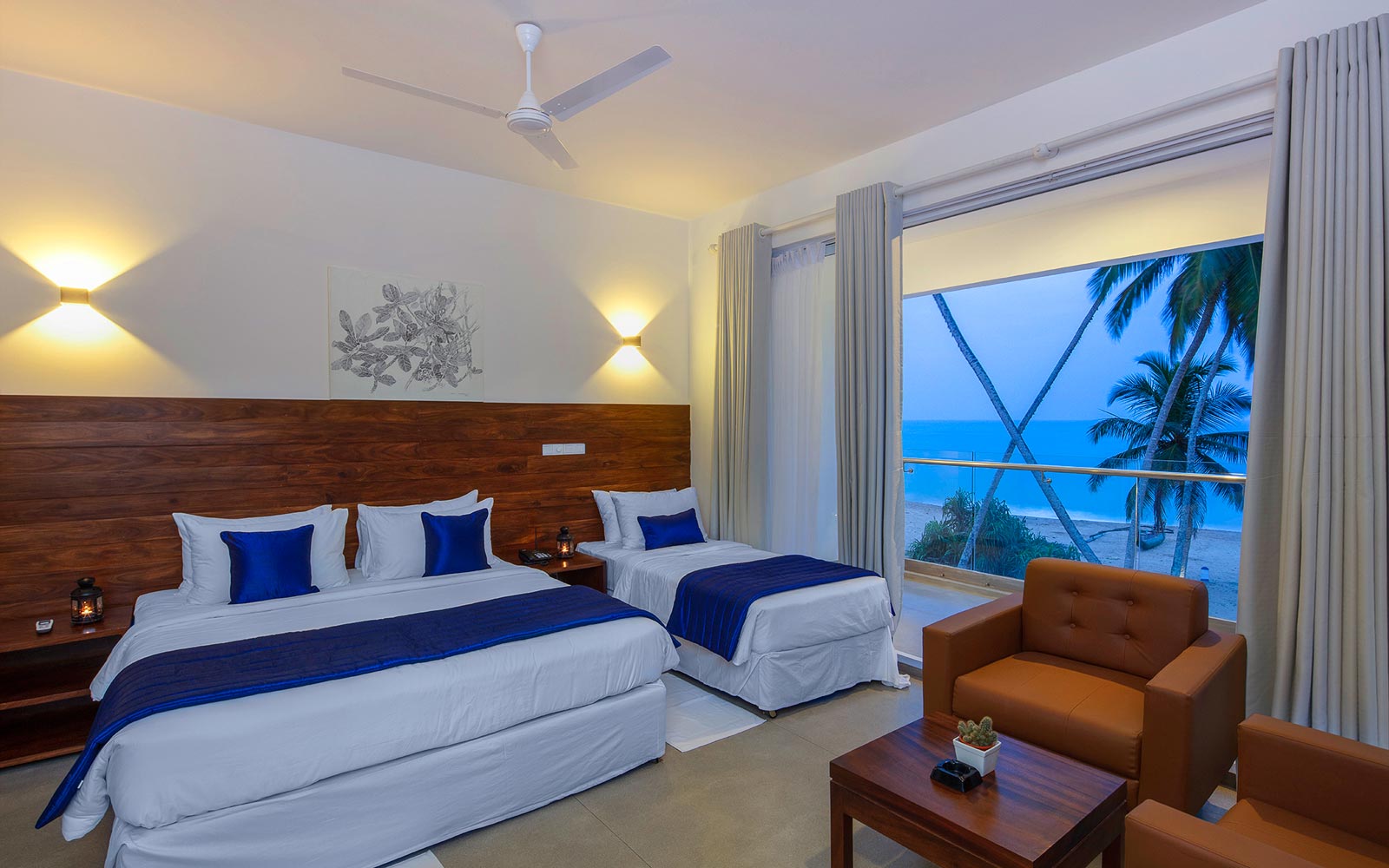 Room in the private resort villa at dusk, with a balcony overlooking palms and the ocean