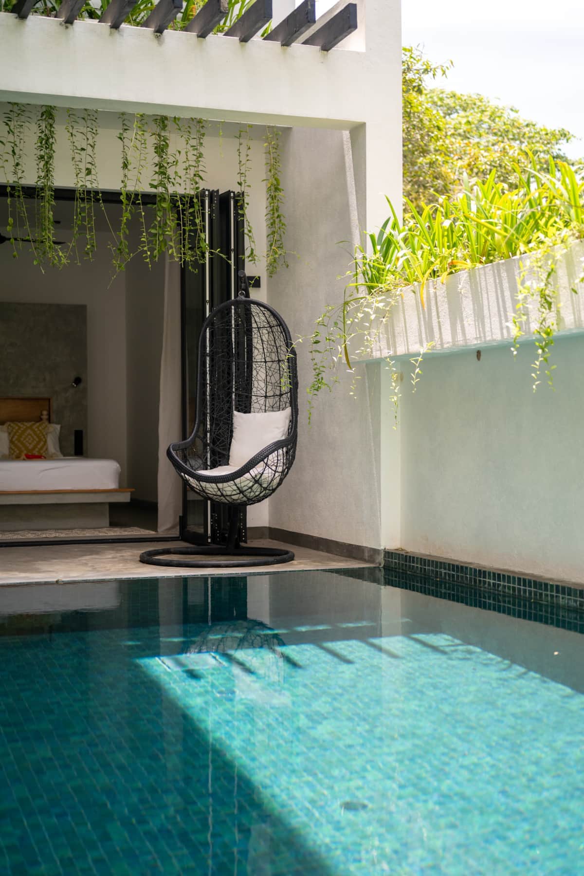 Poolside Apartment bedroom opening onto the private pool, with a hanging egg chair