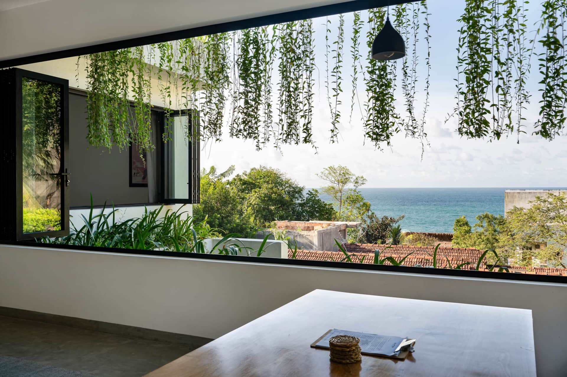 Open-plan living and dining area at Sudu Villa with hanging vines and an ocean view