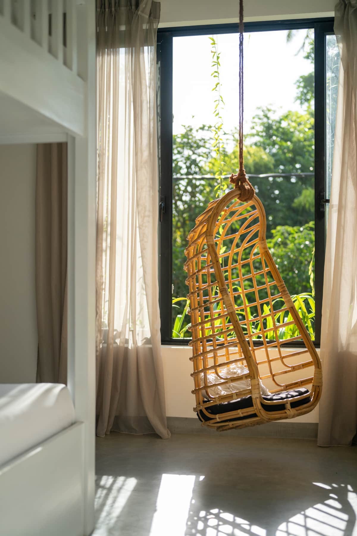 Hanging rattan chair beside a bedroom window at Sudu Villa