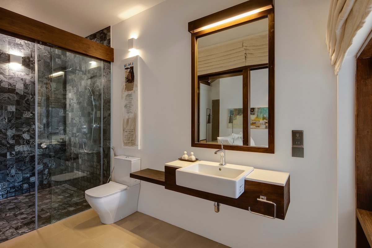 En-suite bathroom with a dark stone rain shower, vessel basin and timber-framed mirror