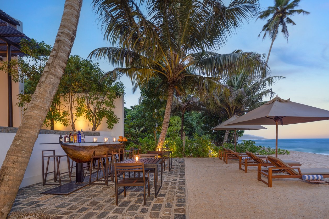 The beach bar terrace at Three Gables Boutique Villa at dusk, with sun loungers on the private beach