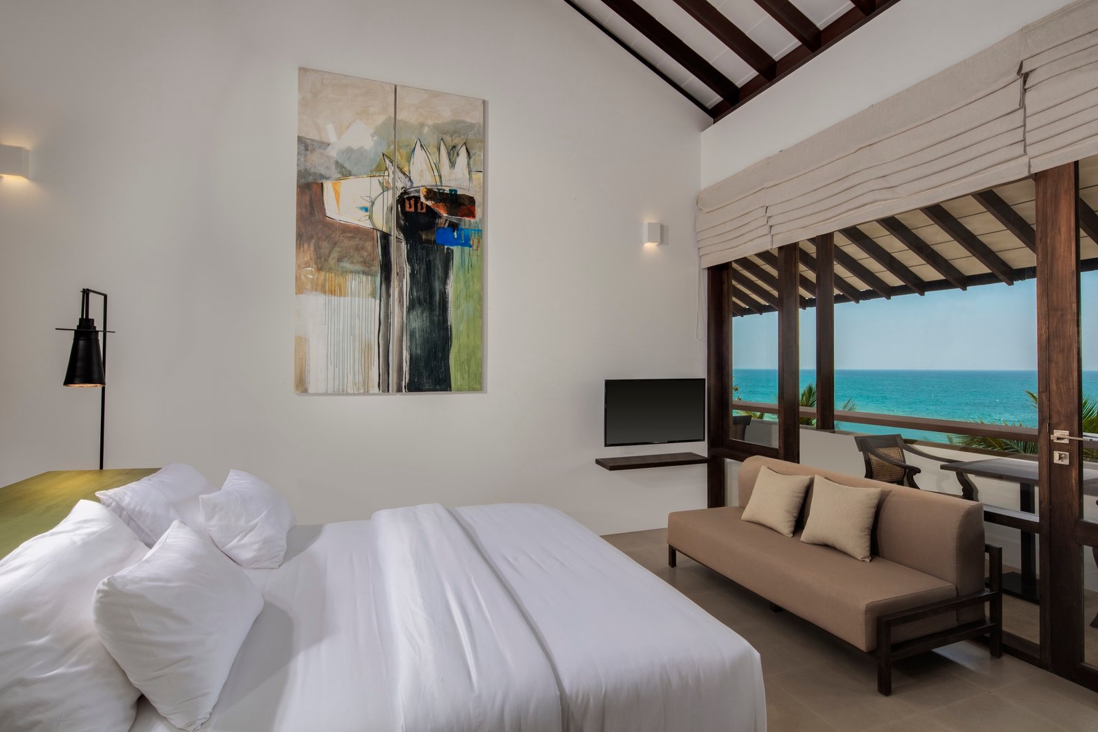 Deluxe King Room at Three Gables Boutique Villa with artwork above the bed and a balcony facing the turquoise ocean
