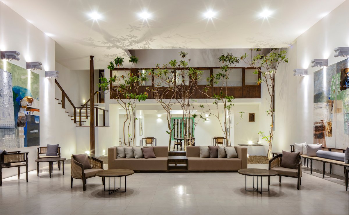 The double-height living lounge at Three Gables Boutique Villa with indoor trees, sofas and large artworks