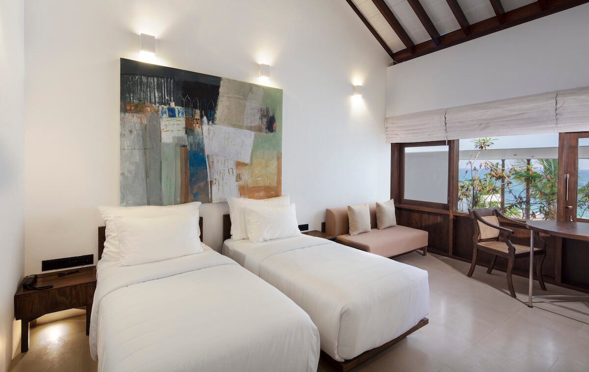 Deluxe Twin Room at Three Gables Boutique Villa with twin beds, artwork and glass doors to the sea view