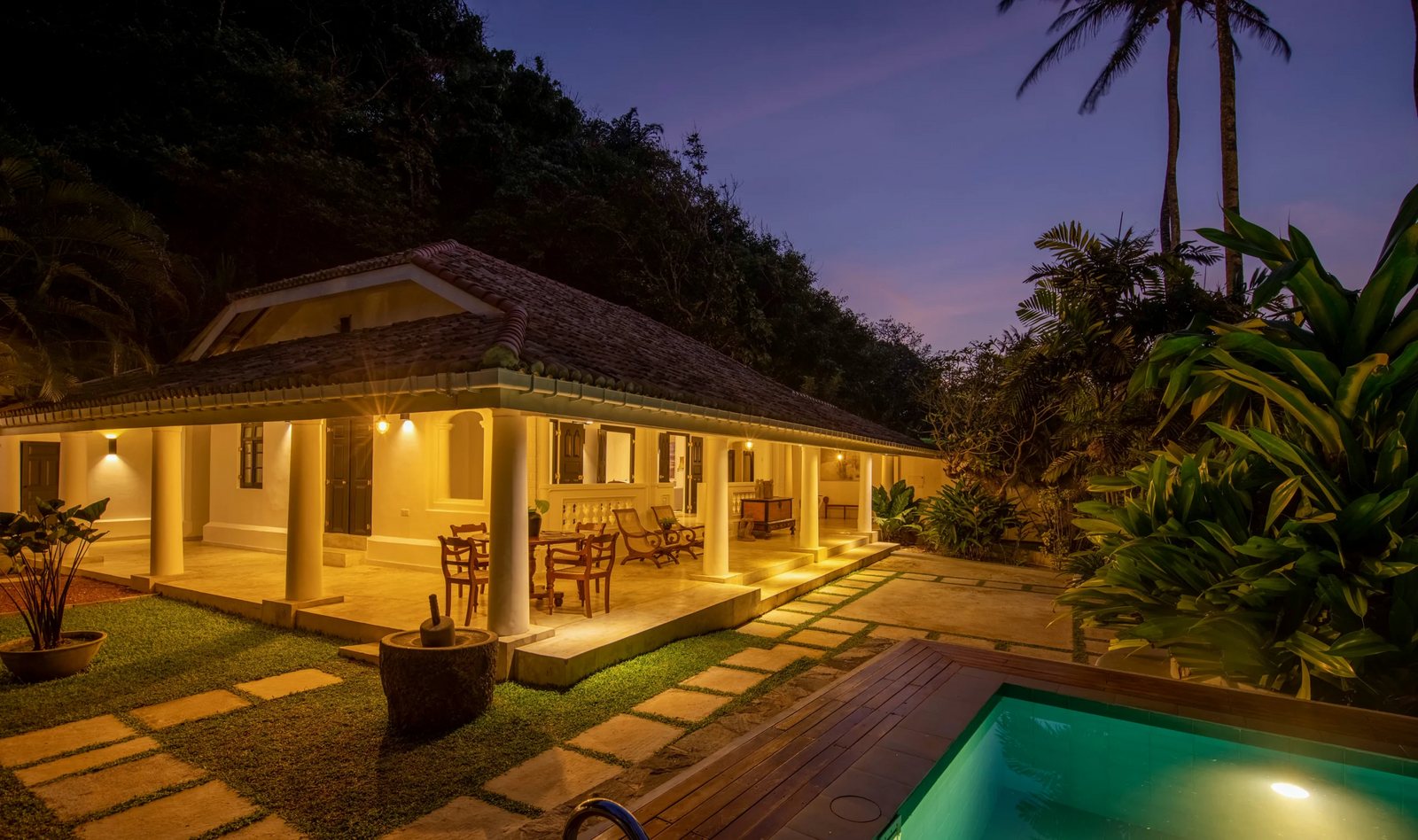 Villa exterior at dusk with the pool lit